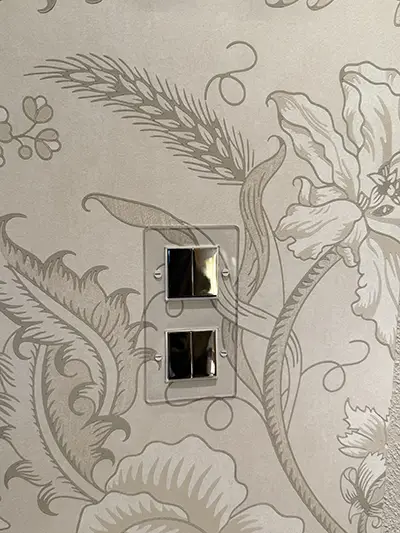 Panneau d'interrupteurs décoratifs en laiton, inox et aluminium posés sur fond neutre