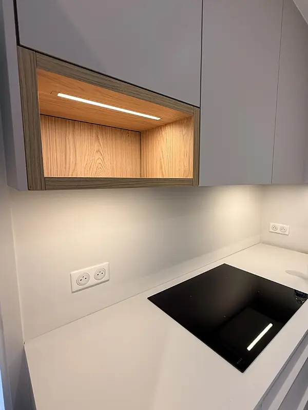 Cuisine rénovée avec bandeau LED encastré sous un meuble ouvert, éclairage indirect pour le plan de travail