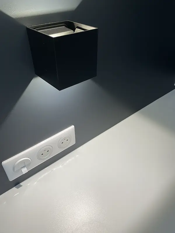 Salle de bain rénovée avec appliques murales symétriques encadrant un miroir, éclairage doux et chaleureux