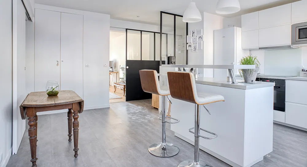 Verrière intérieure noire séparant la cuisine du salon dans un appartement rénové